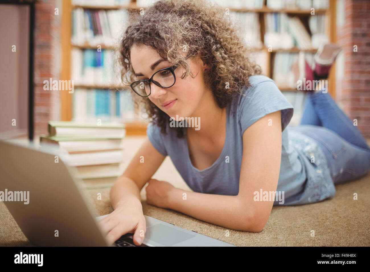 Pretty student in library using laptop Stock Photo - Alamy