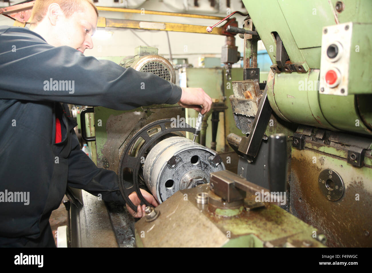 Young worker operates metal detail processing at turning lathe Stock Photo