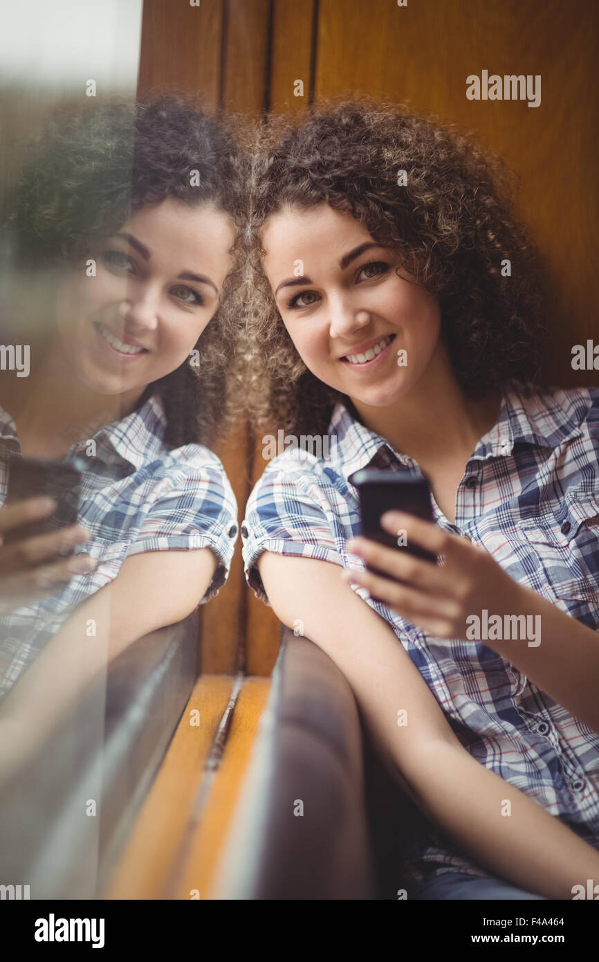 Pretty student sitting by the window using phone Stock Photo