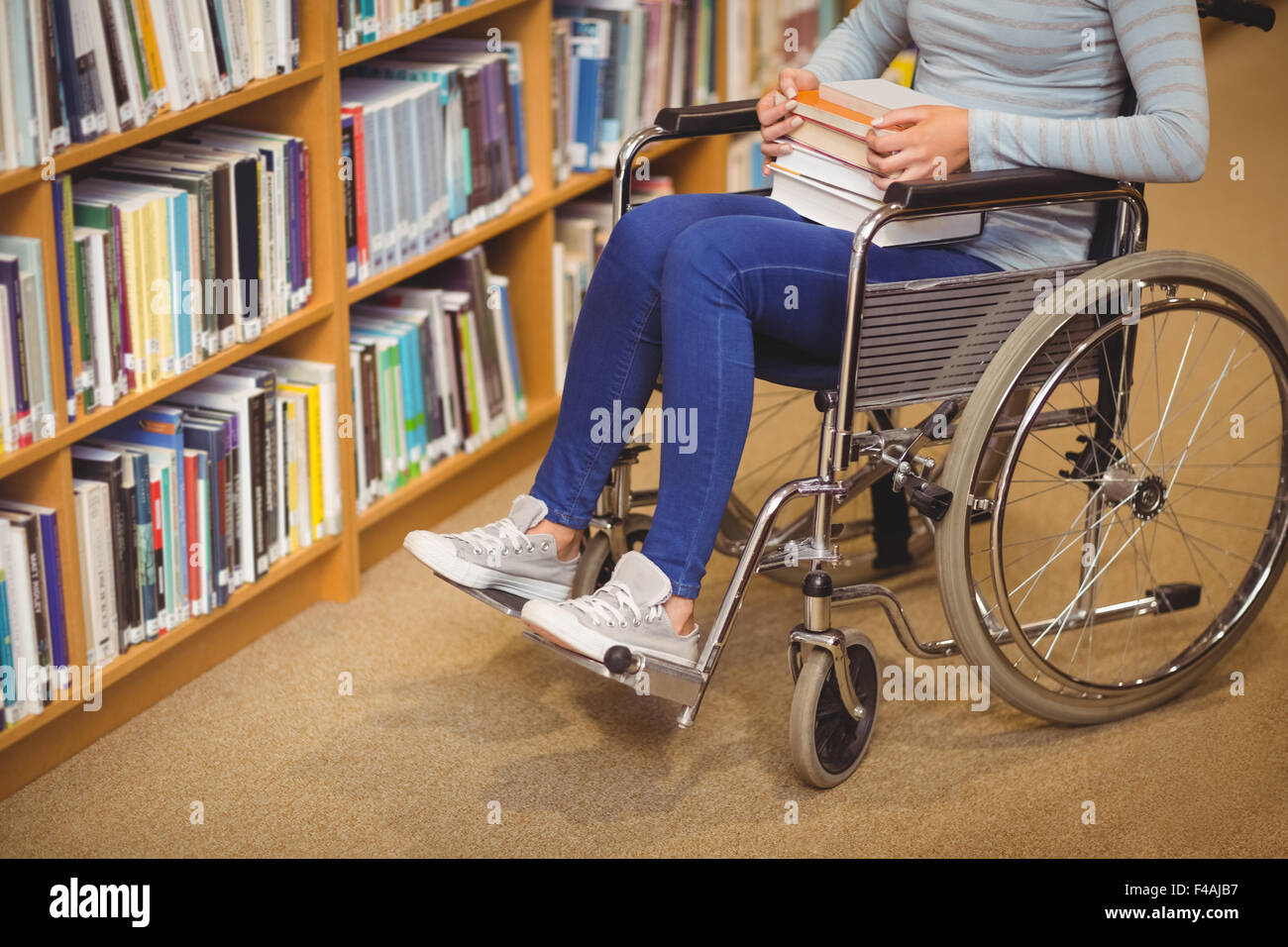 Disabled female student with books on wheelchair Stock Photo