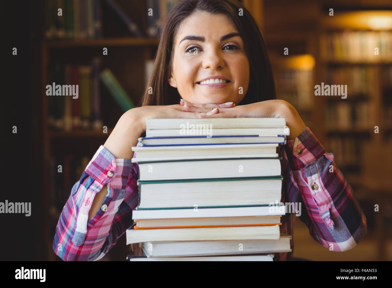 Female student leaning on book stack Stock Photo