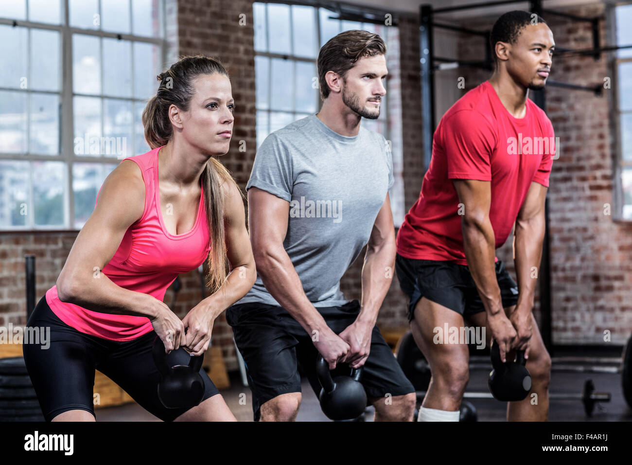 Three fit sporty people lifting kettlebell Stock Photo Alamy