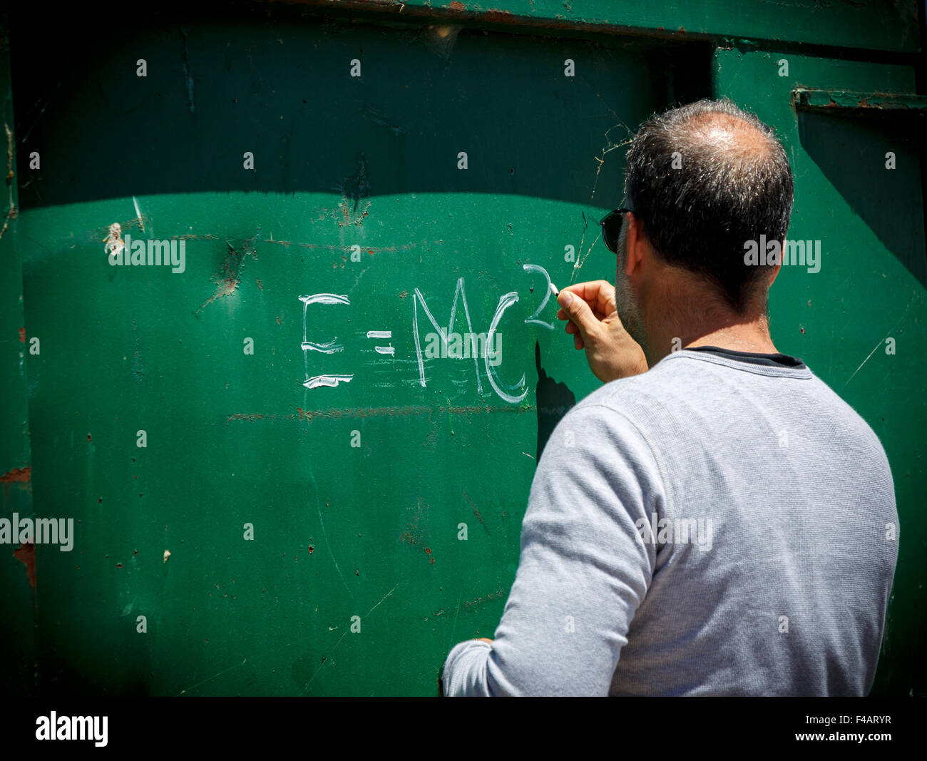 Man writing E=MC2  Albert Einstein's theory of special relativity on the side of a metal sheet Stock Photo