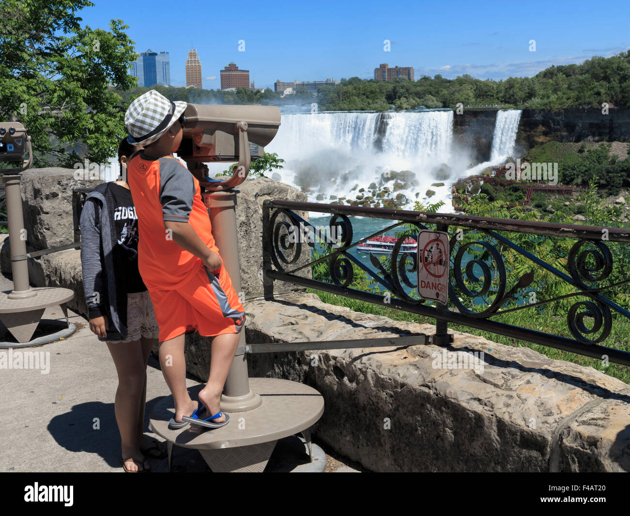 Young boy looking through tourist coin operated binoculars at the American Falls from Niagara Ontario Canada Stock Photo