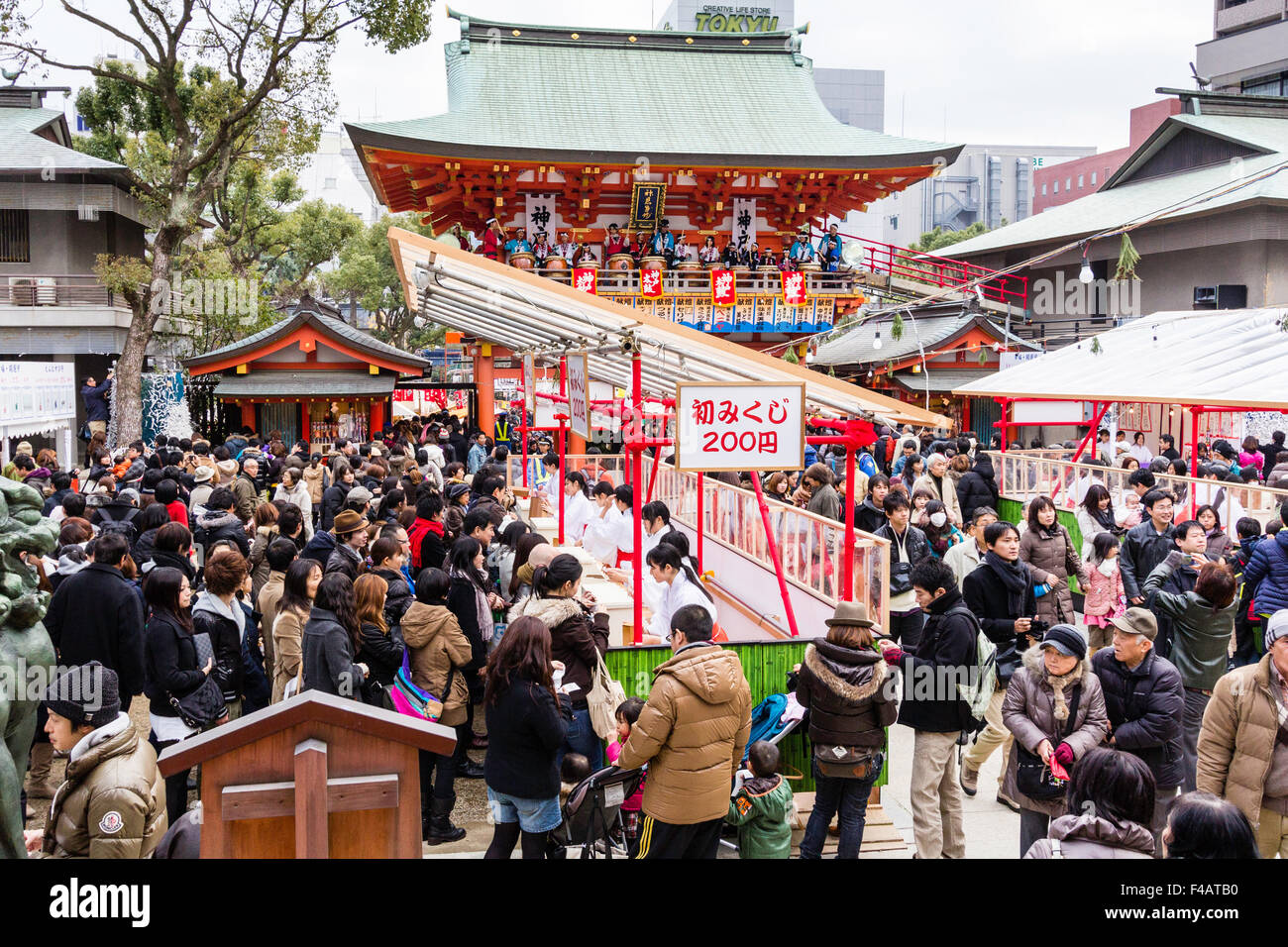 Ikuta shrine, Kobe. New Year. Crowds filling the shrine buying fortune papers, omikuji, from Miko, shrine maidens at specially constructed counter. Stock Photo