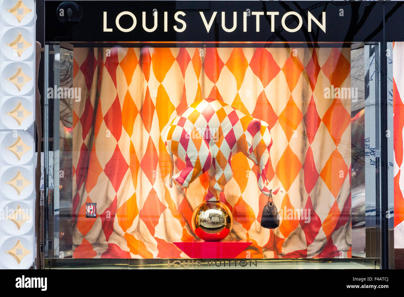 Japan. Louis Vuitton display window with chequered cloth stuffed elephant balancing on silver ball holding handbag with trunk, chequered background. Stock Photo