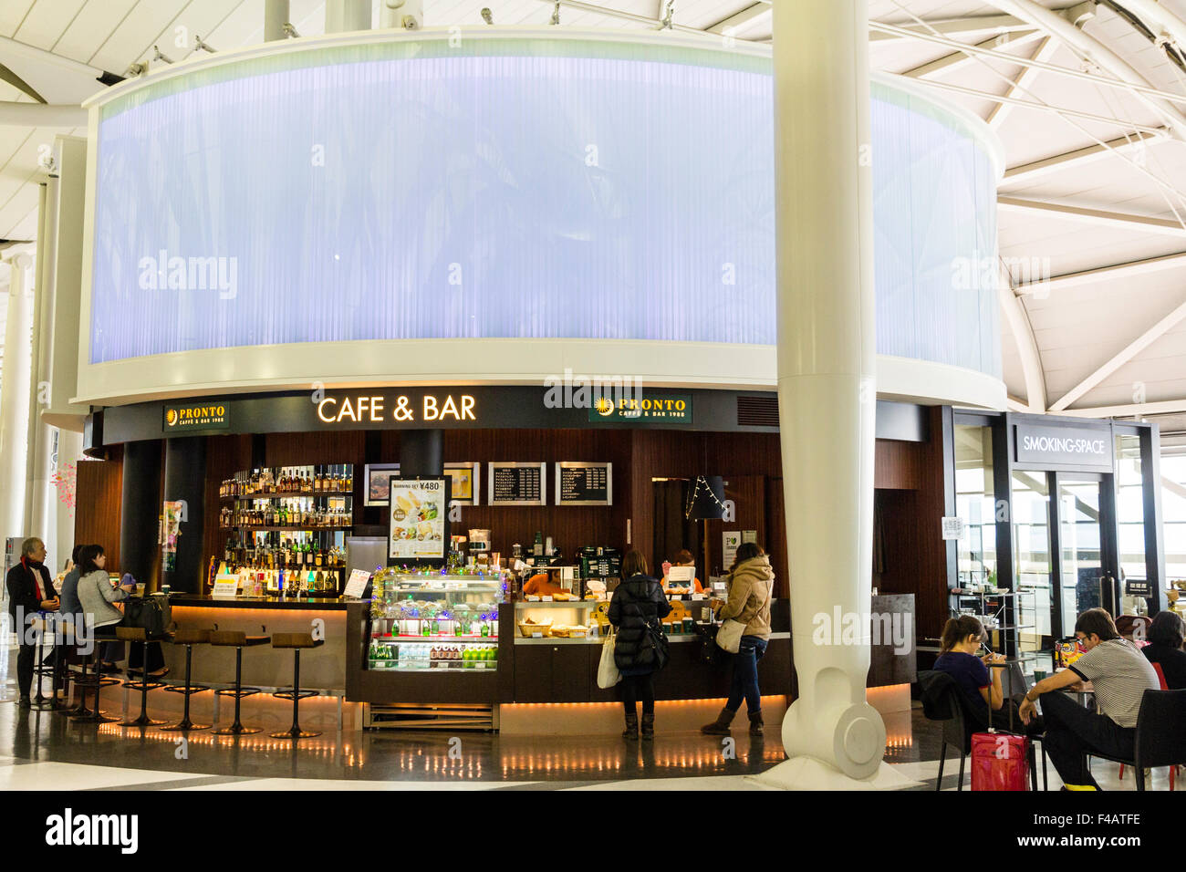 Interior of Kansai Airport, Osaka, Japan, the International Departures lounge. Coffee bar café with two passengers at bar being served, others sitting. Stock Photo