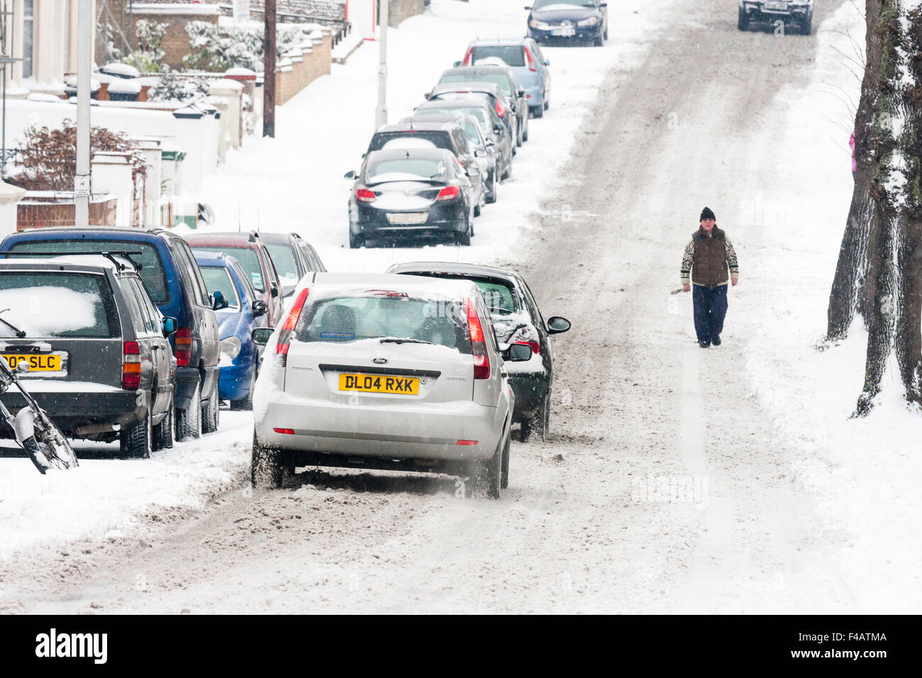 Bad weather, England, Ramsgate town. Snow covered main road with cars parked and cars attempting to drive along in hazadous conditions after snowfall. Stock Photo