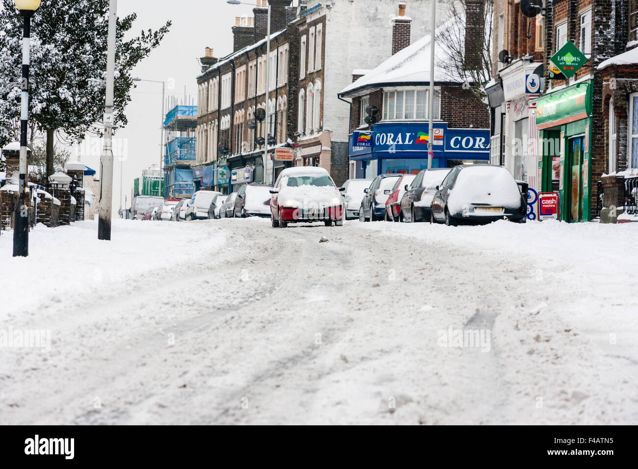 Bad weather, England, Ramsgate town. Snow covered main road with cars parked and car attempting to drive along in hazadous conditions after snowfall. Stock Photo
