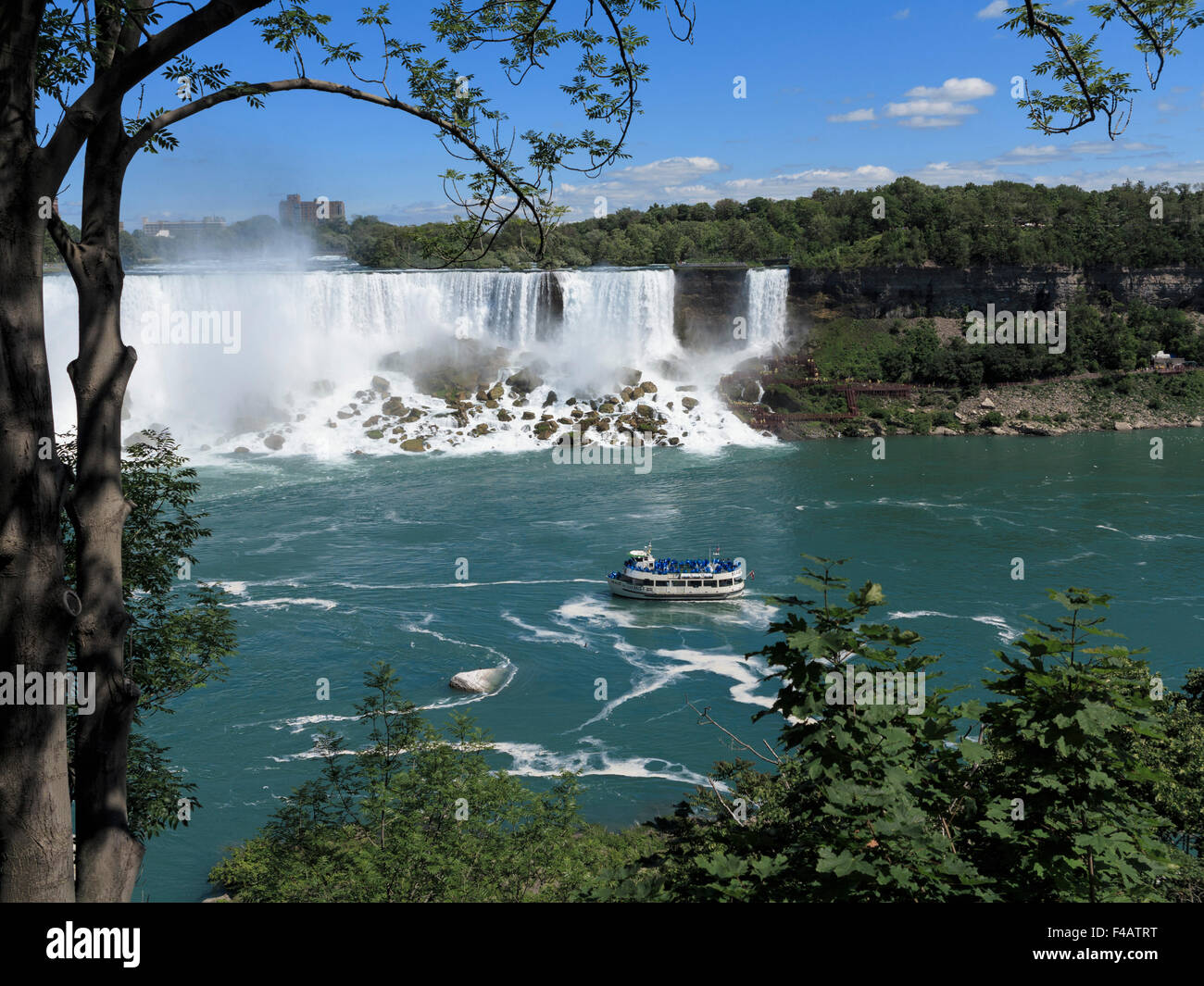 American Falls and Maid of the Mist tour boat framed by a tree on the Canada side of the river Niagara Stock Photo