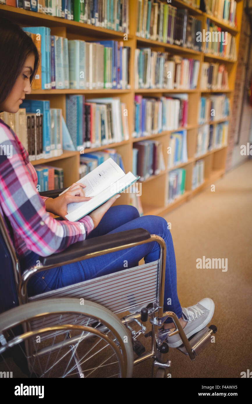 Concentrated disabled female student reading book Stock Photo