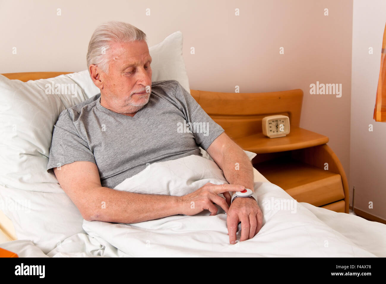 Senior Rufhilfe with emergency phone in bed Stock Photo