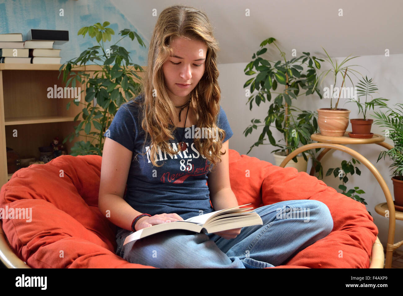 Teenager reads relaxed in the chair couch Stock Photo Alamy