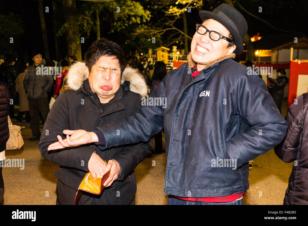 New Year's eve, Nishinomiya shrine, midnight. Two Japanese men pulling funny faces and laughing at the viewer while showing how cold the night is. Stock Photo