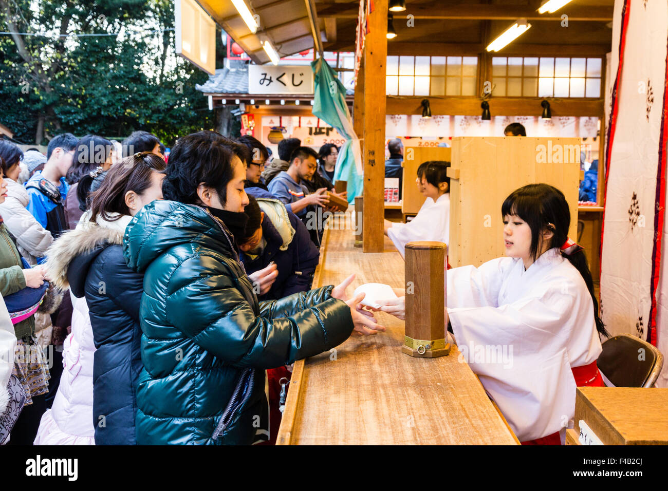 Japan, Nishinomiya shrine, New year Day, Shogatsu. Woman buying omikuji ...