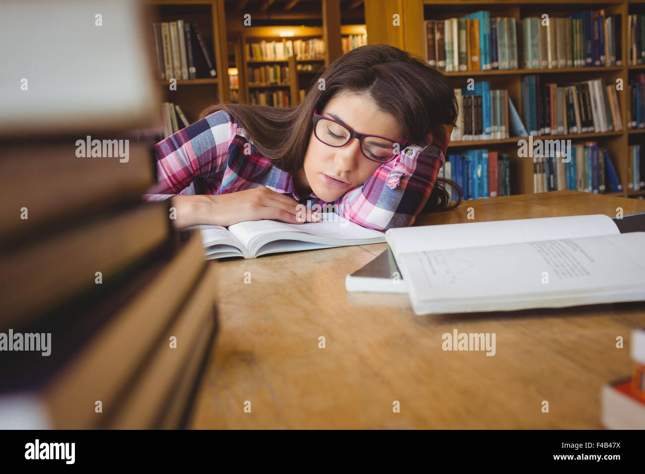 Female student sleeping with head on book at table Stock Photo