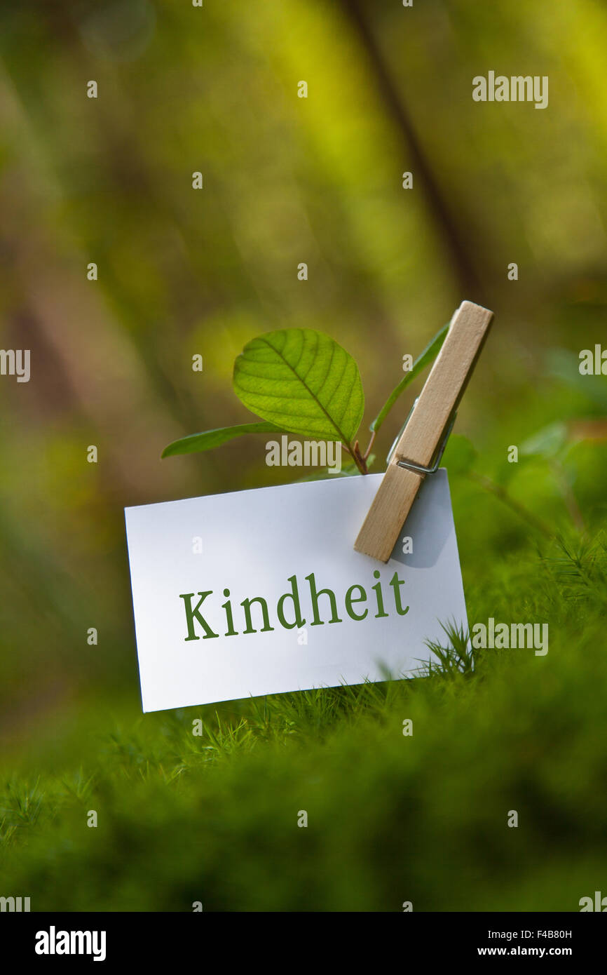 „Kindheit“ on paper with a seedling Stock Photo