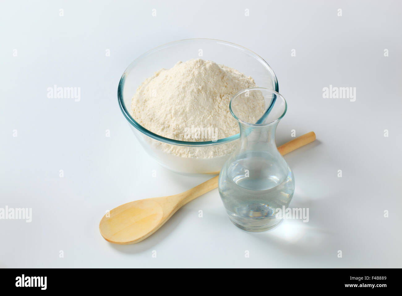 white wheat flour in a glass bowl and a carafe of cold water Stock Photo