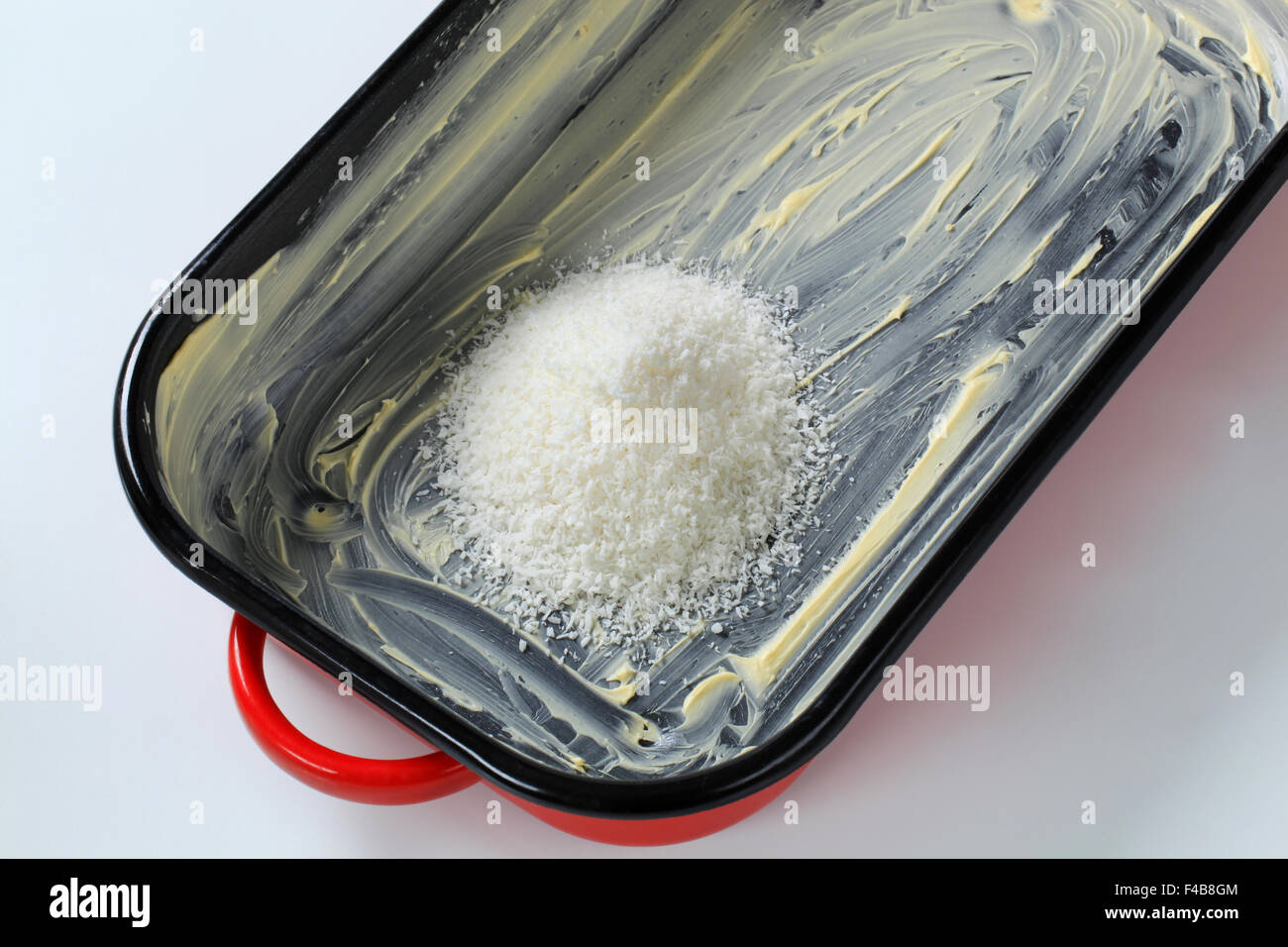 heap of desiccated coconut in greased baking pan Stock Photo