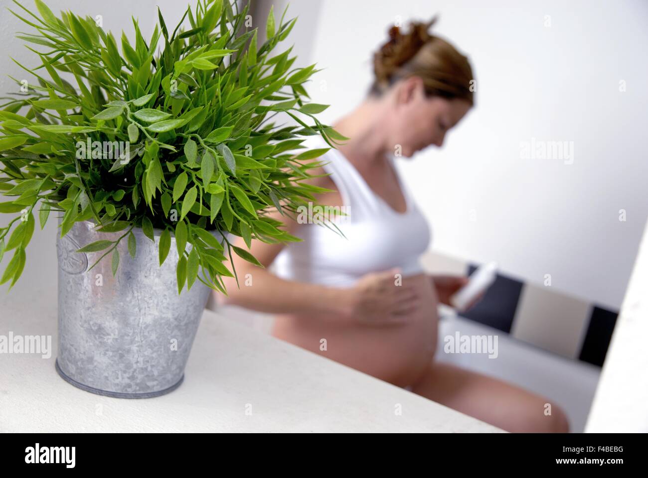pregnant woman applying body lotion Stock Photo