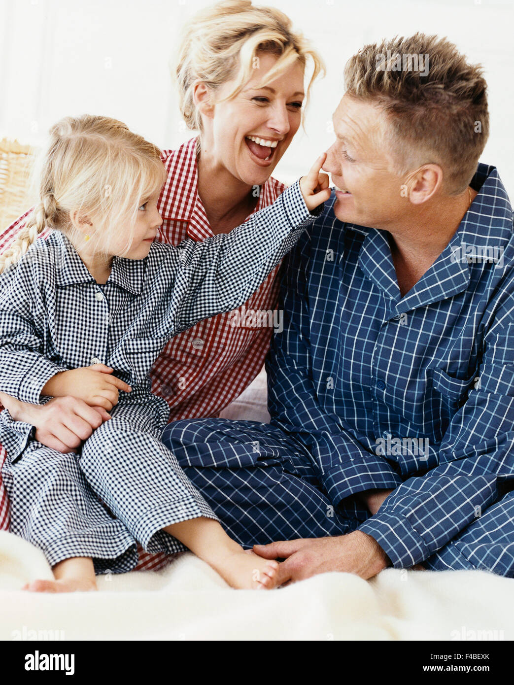 Dad, mom and girl sits in bed and laughs Stock Photo - Alamy