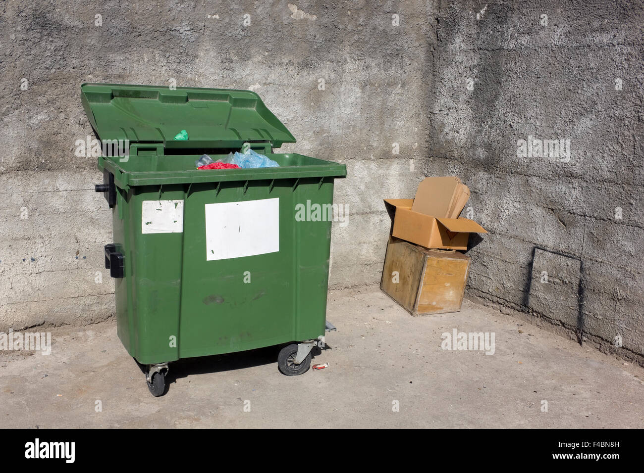 Green garbage mass production container near of concrete walls Stock