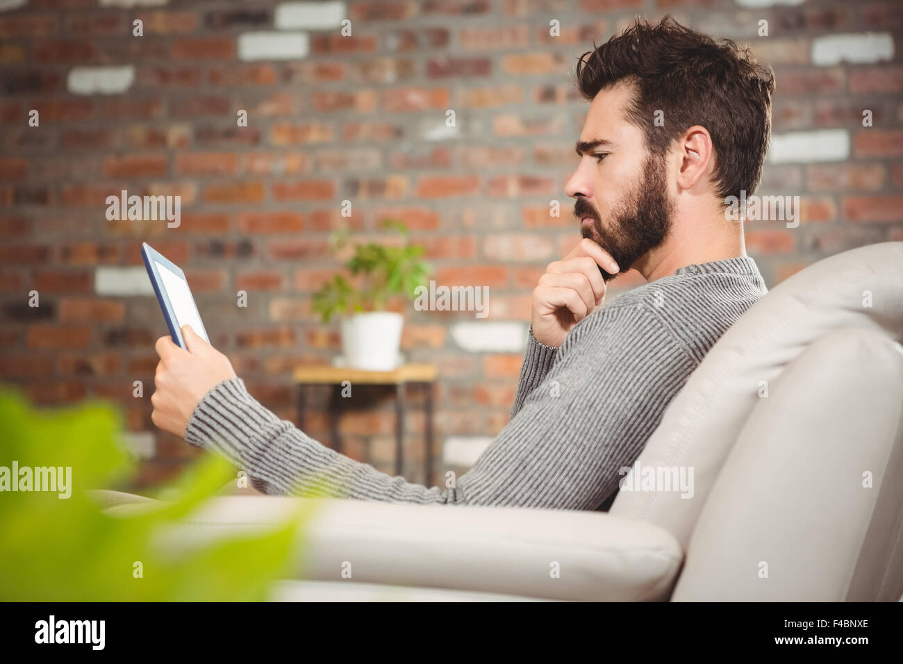 Side view of thoughtful man looking at digital tablet Stock Photo