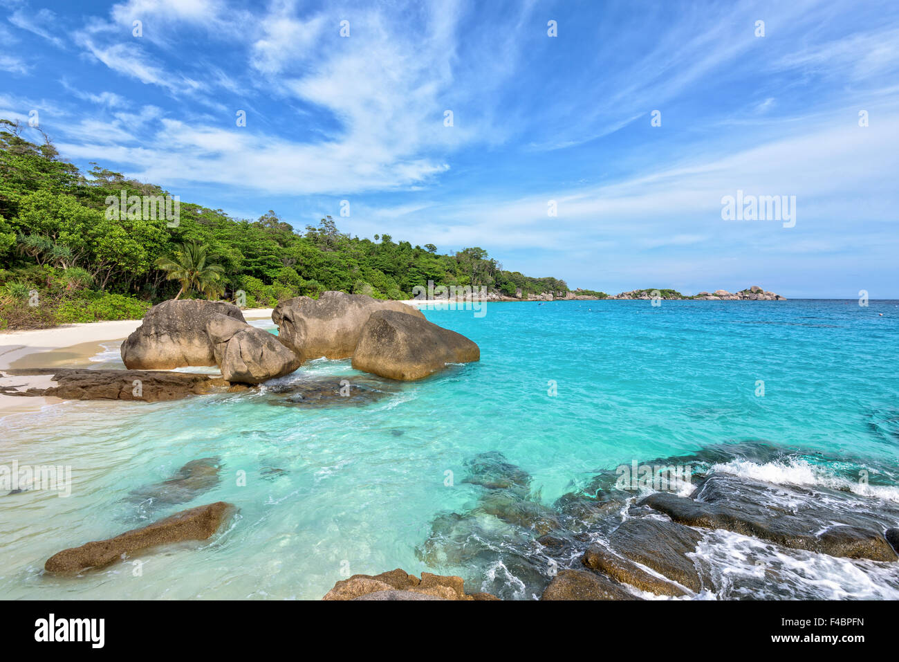 Beautiful landscape of blue sky sea sand and white waves on beach near the rocks during summer at Koh Miang island in Ko Similan Stock Photo