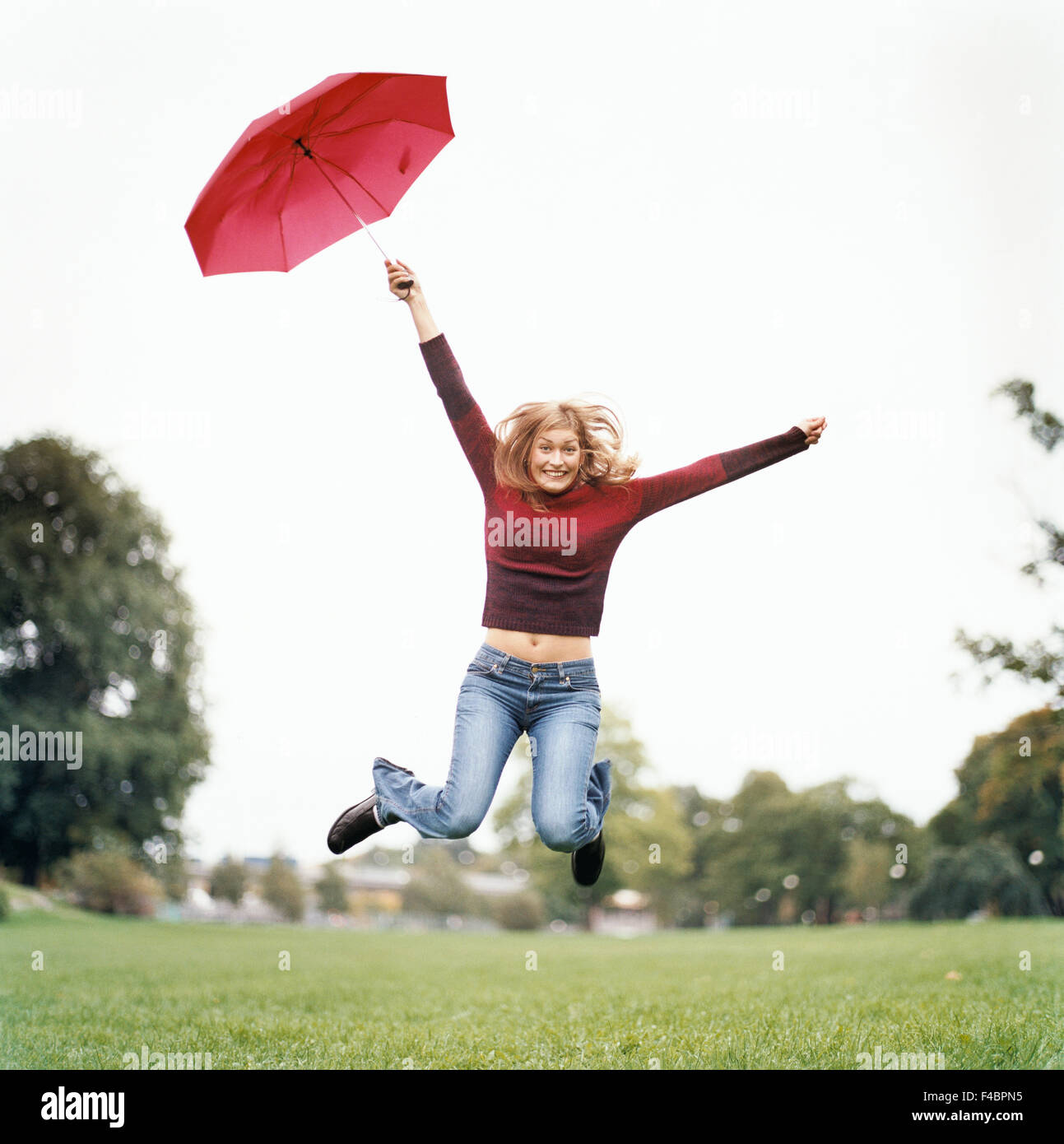 Woman jumps up in the air on lawn with umbrella in hand Stock Photo - Alamy