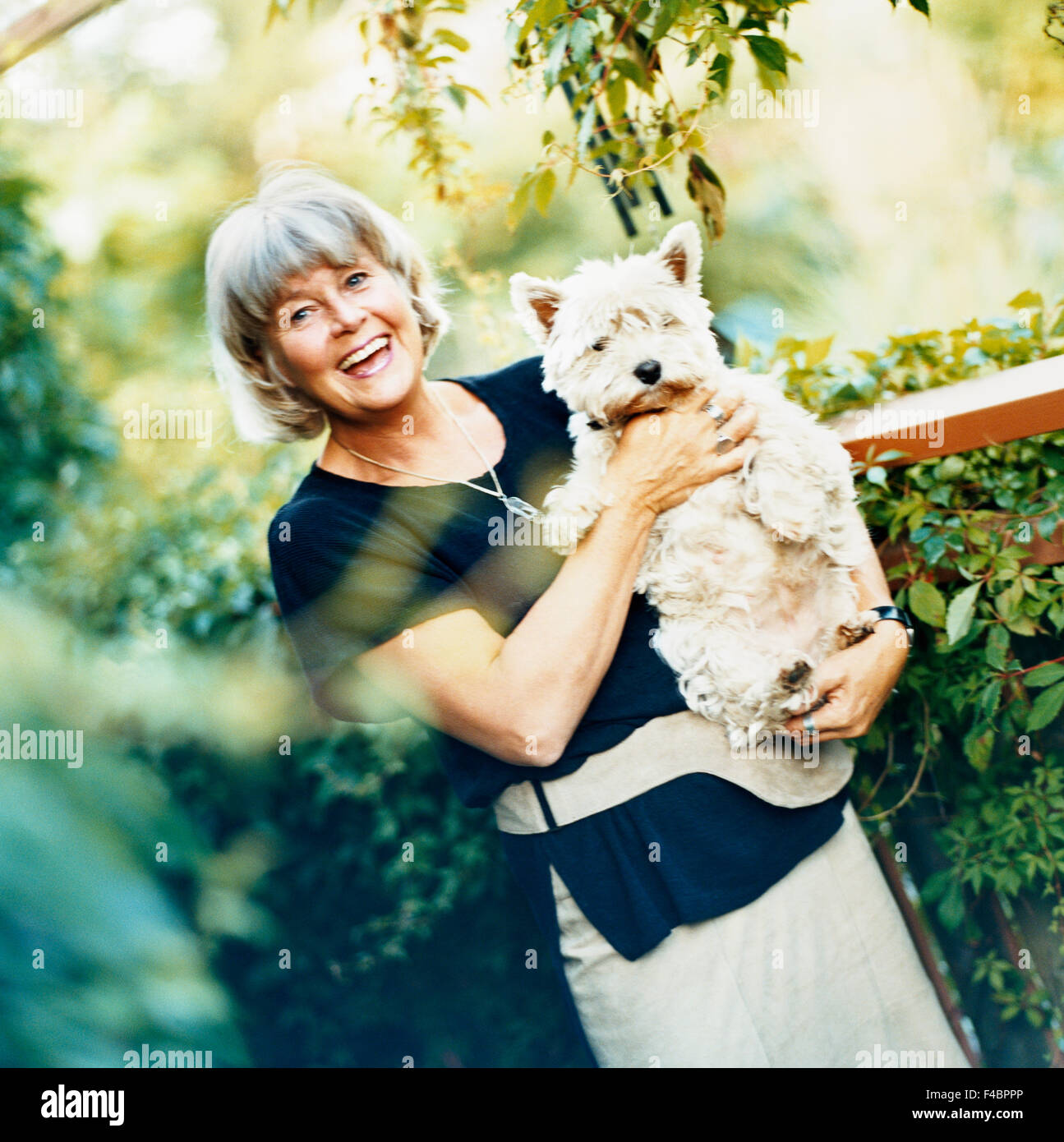 Woman standing in the garden with the dog in her arms Stock Photo - Alamy