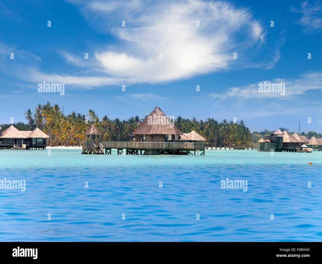 Huts in the sea and a palm tree Stock Photo