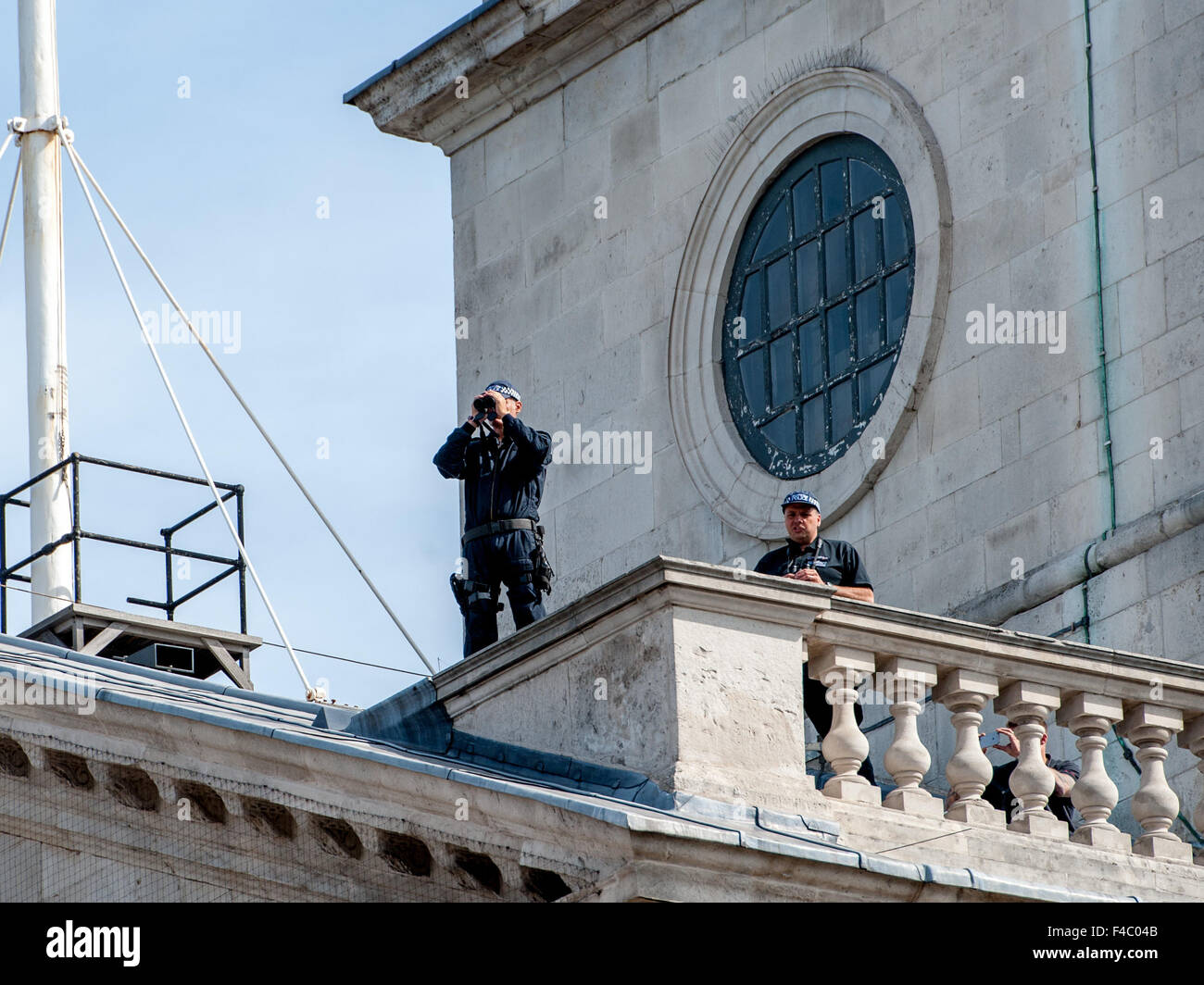 Police officers with binoculars look out from the roof top of St Martin-in-the-Fields church as officers with sniffer dogs patrol the street below prior to the 70th Victory over Japan Day commemorations held in Central London.  Featuring: View, Atmosphere Stock Photo