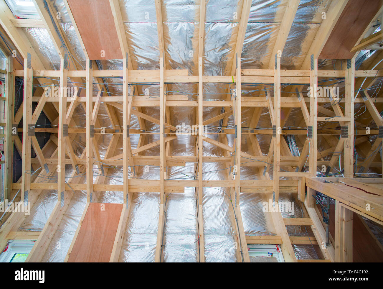 Looking up at a newly constructed roof with timber trusses and insulation Stock Photo