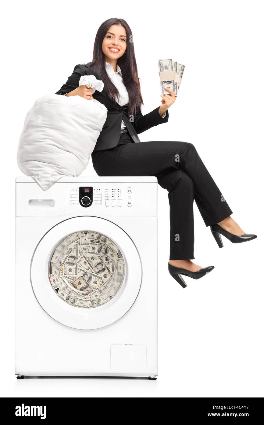 Young businesswoman laundering money in a washing machine and looking at the camera isolated on white background Stock Photo