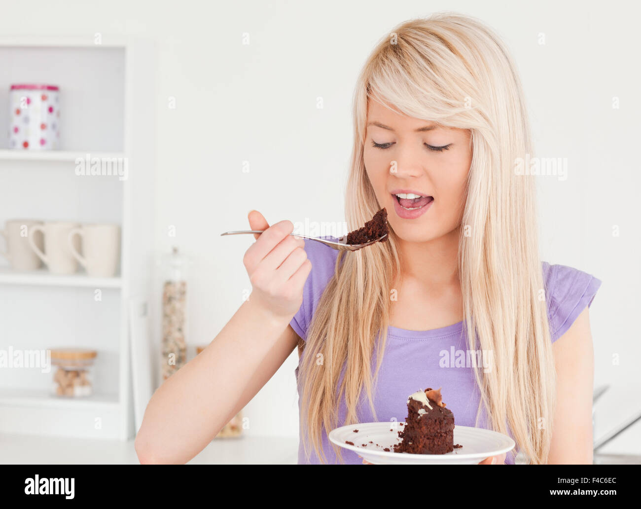 Smiling blonde woman eating cake Stock Photo Alamy