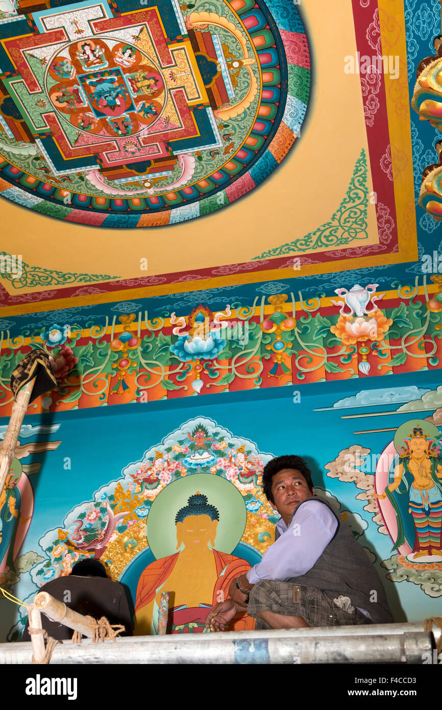 India, Jammu & Kashmir, Ladakh, Stok gompa, Nepali artist decorating temple interior below Golden Buddha statue Stock Photo