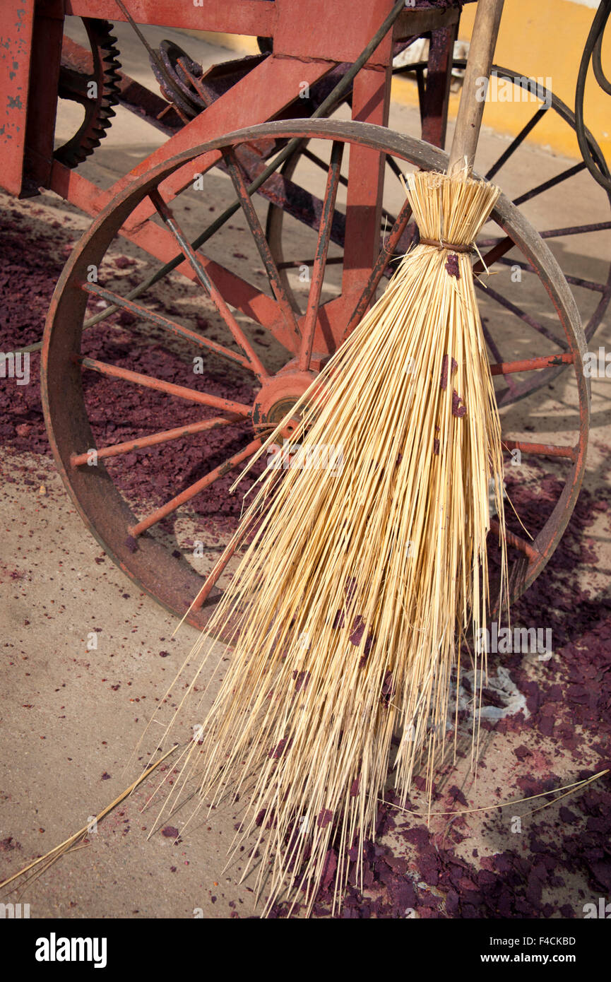 China, Ningxia. Straw broom, used to sweep grape skins and seeds, leans against a steel-wheeled machine at Helan Mountain winery. Stock Photo