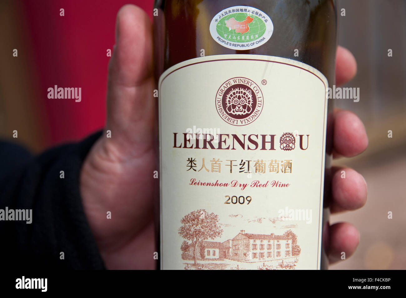 China, Ningxia. Feng Qing, chairman of Leirenshou Grape Winery, holds a bottle of his wine. Stock Photo
