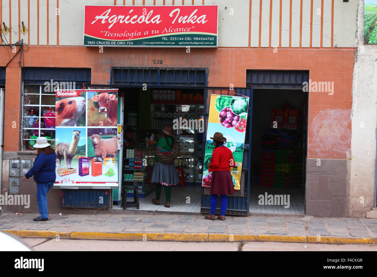 Quechua women entering a shop selling fertilizers and agricultural products, Cusco, Peru Stock Photo