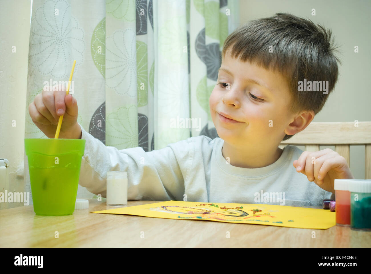 Happy Little Boy Painting at the table in the home. Stock Photo