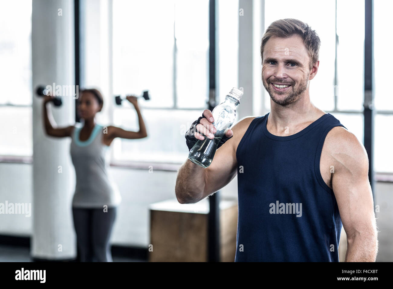 Young Bodybuilder drinking a bottle of water after the training Stock Photo