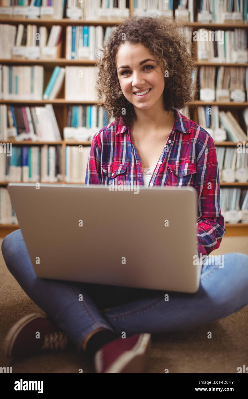 Pretty student in library using laptop Stock Photo - Alamy