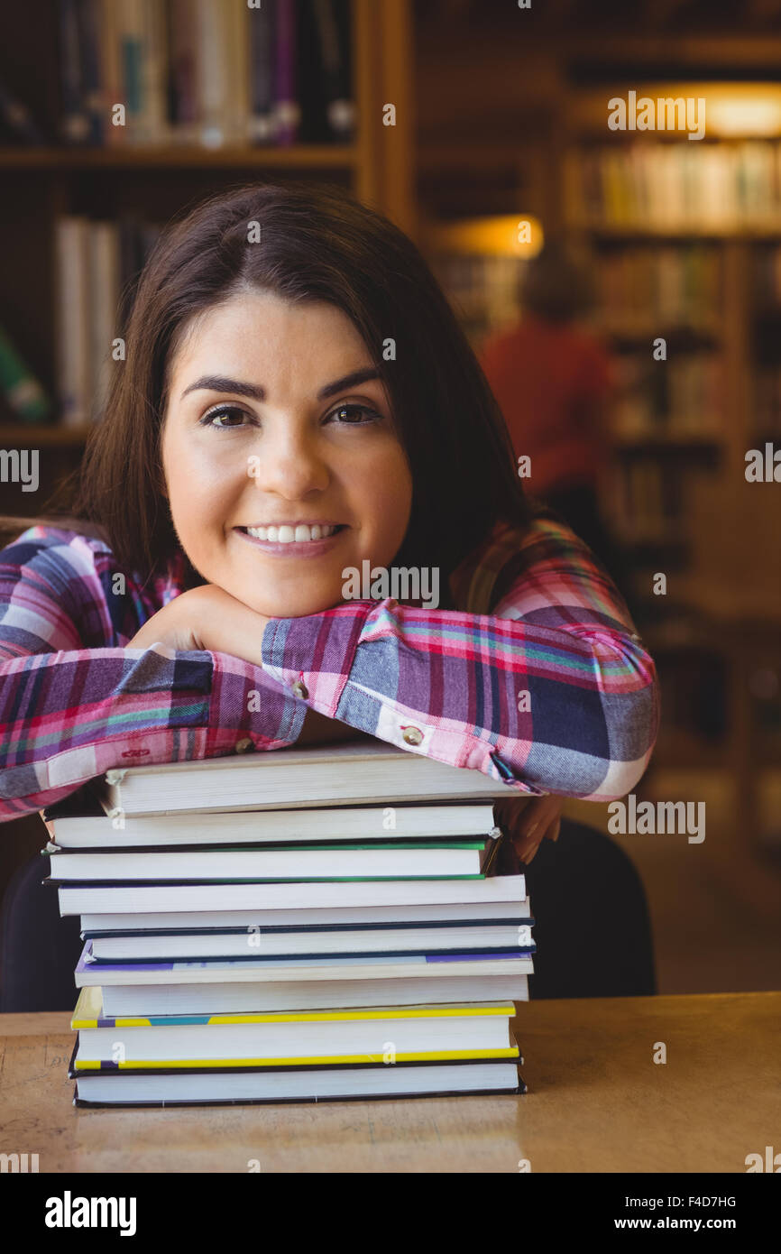 Cheerful female student leaning on book stack Stock Photo - Alamy