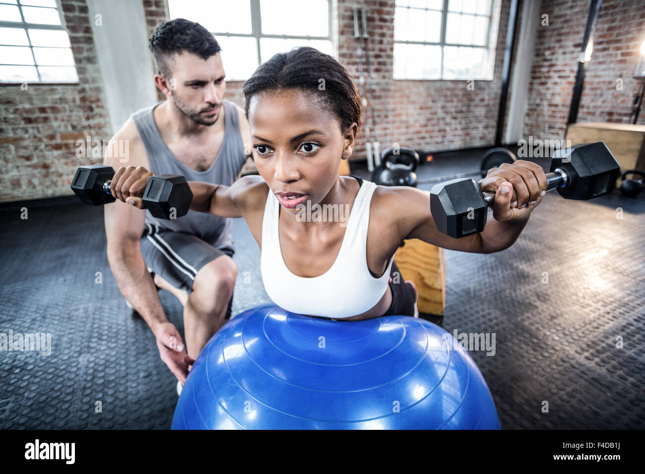 Personal trainer working with client holding dumbbell Stock Photo