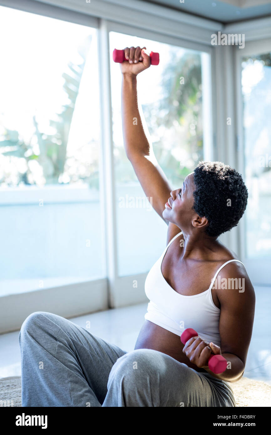 Woman exercising with dumbbells while sitting Stock Photo