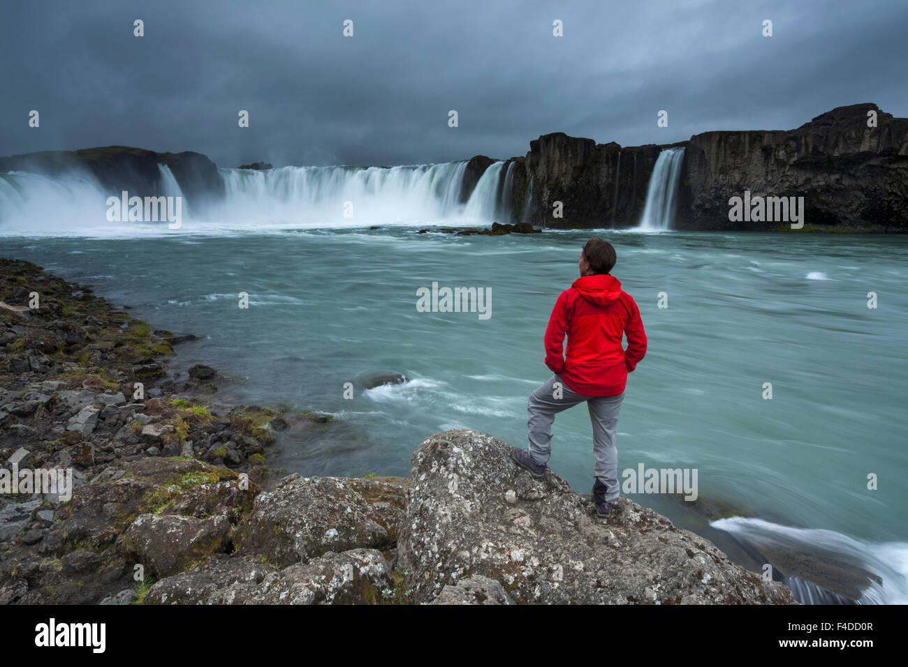 Person beneath Godafoss waterfall, Nordhurland Eystra, Iceland. Stock Photo