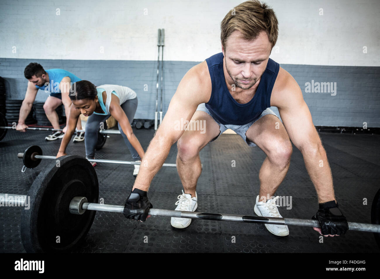 Three muscular athletes liftings barbells Stock Photo