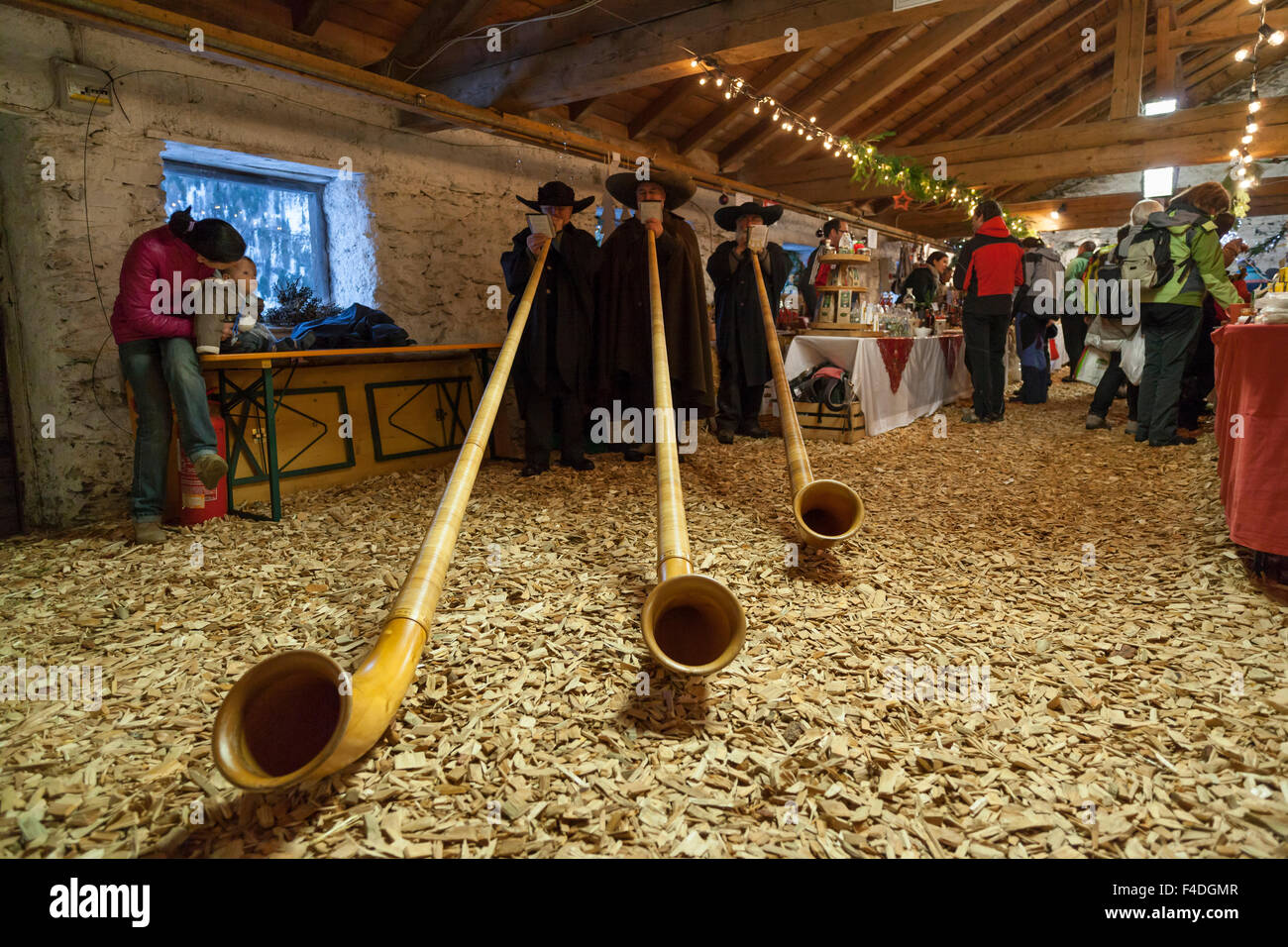 Musicians in traditional garment playing the Alphorn or Alpenhorn on a Christmas Market in Martell Valley (Martello). South Tyrol, Italy. Stock Photo