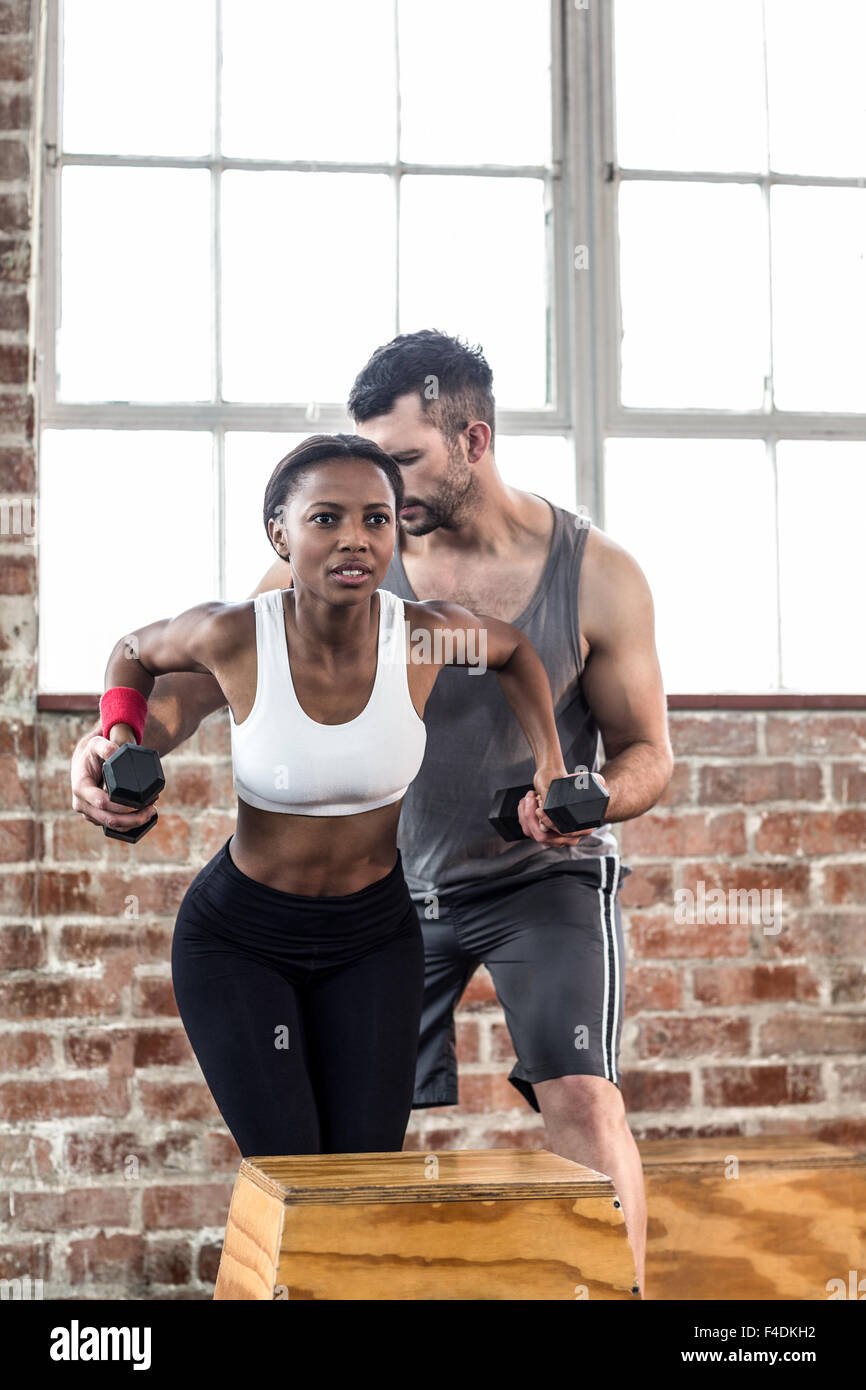 Fit woman lifting dumbbells with her trainer Stock Photo