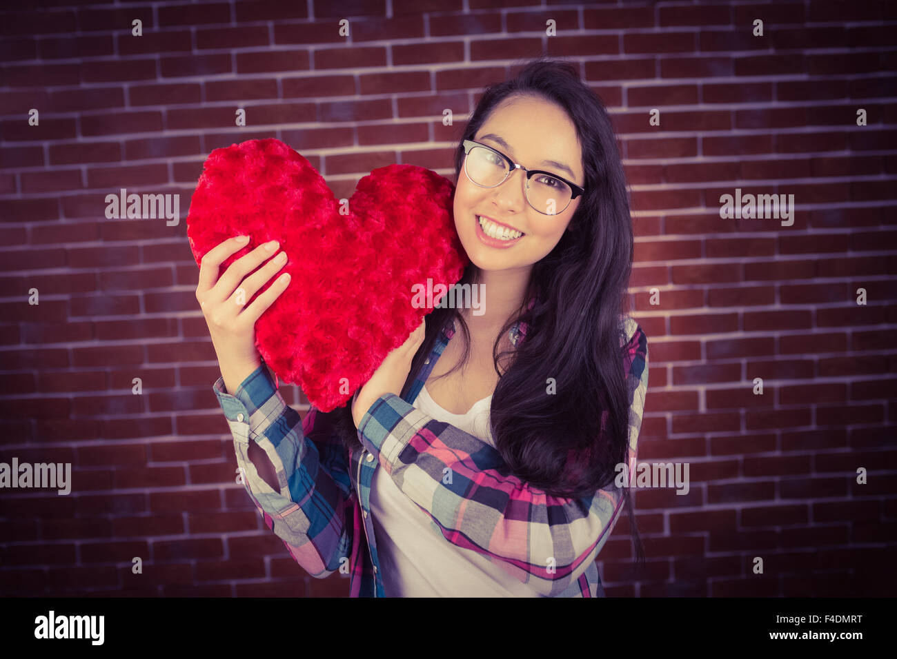 Attractive young woman holding up heart-shaped pillow Stock Photo